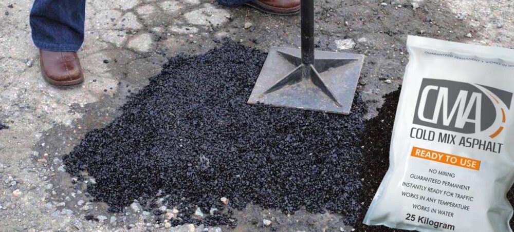 Pothole repair using Cold Mix Asphalt, with a 25-kilogram bag of the product prominently displayed next to a freshly filled pothole and a metal tamper, indicating the compaction process.